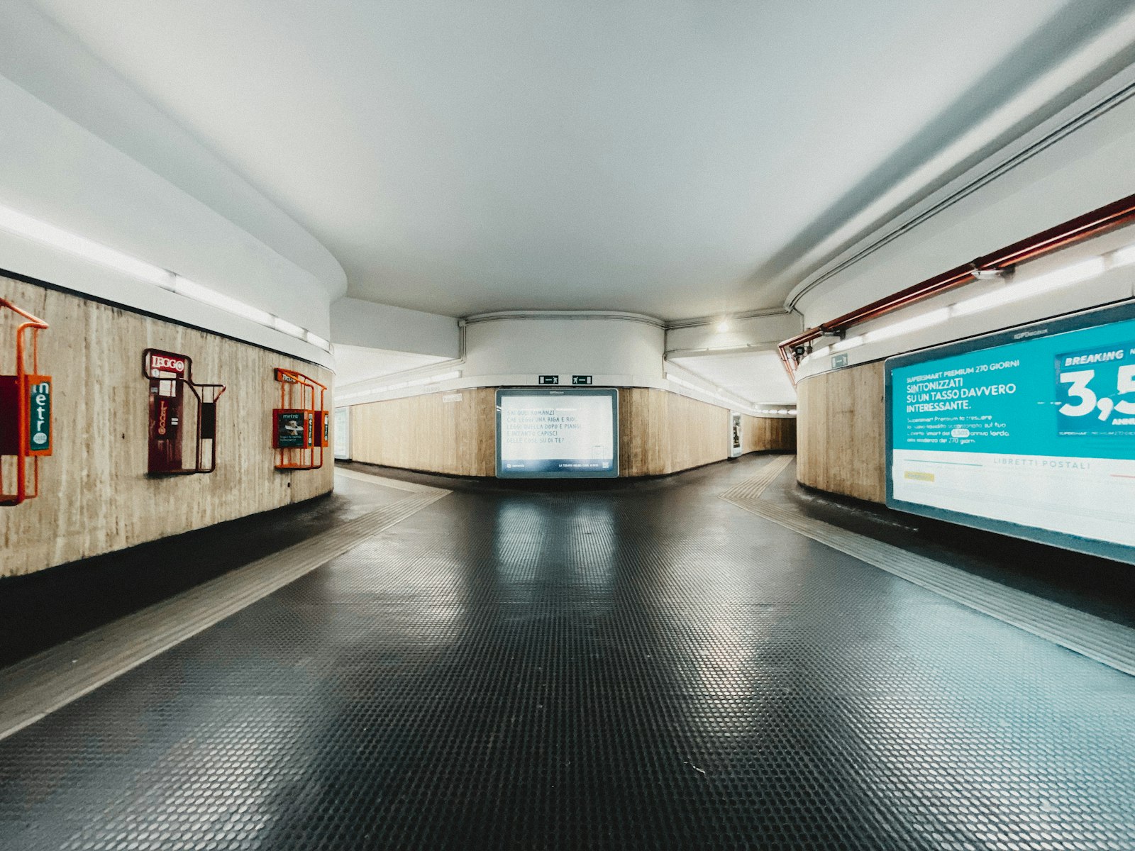 An underground passage in a Rome metro station: light walls, signs, an empty corridor