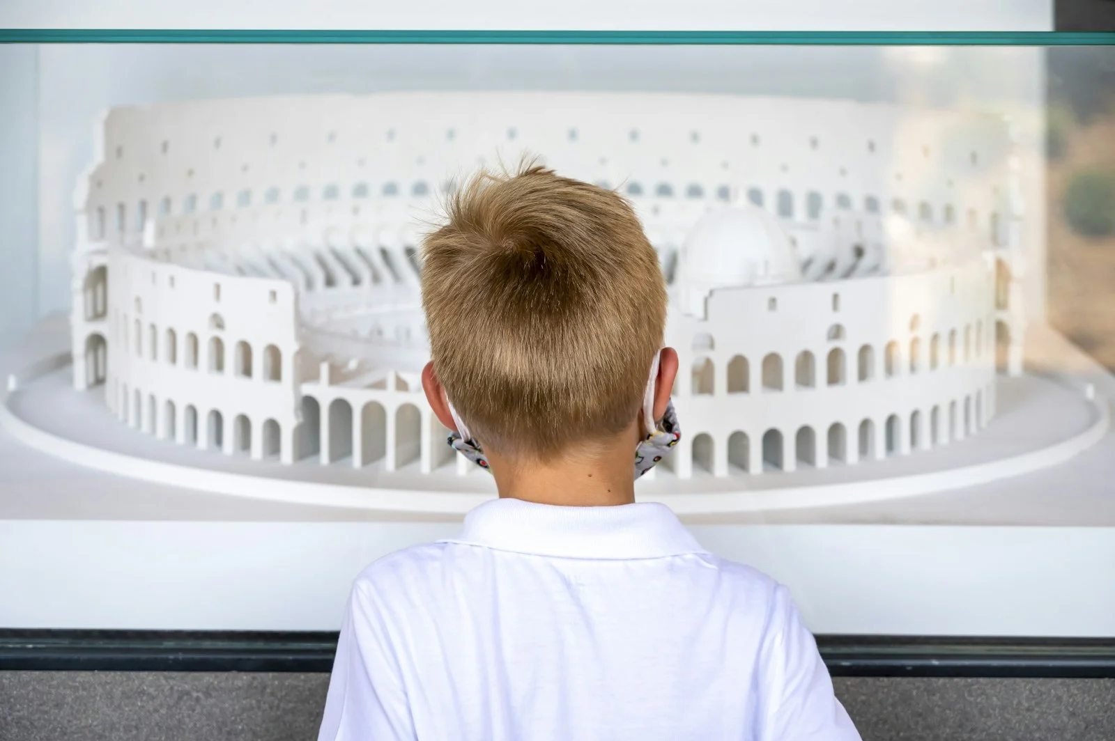 A boy looking at a model of the Colosseum